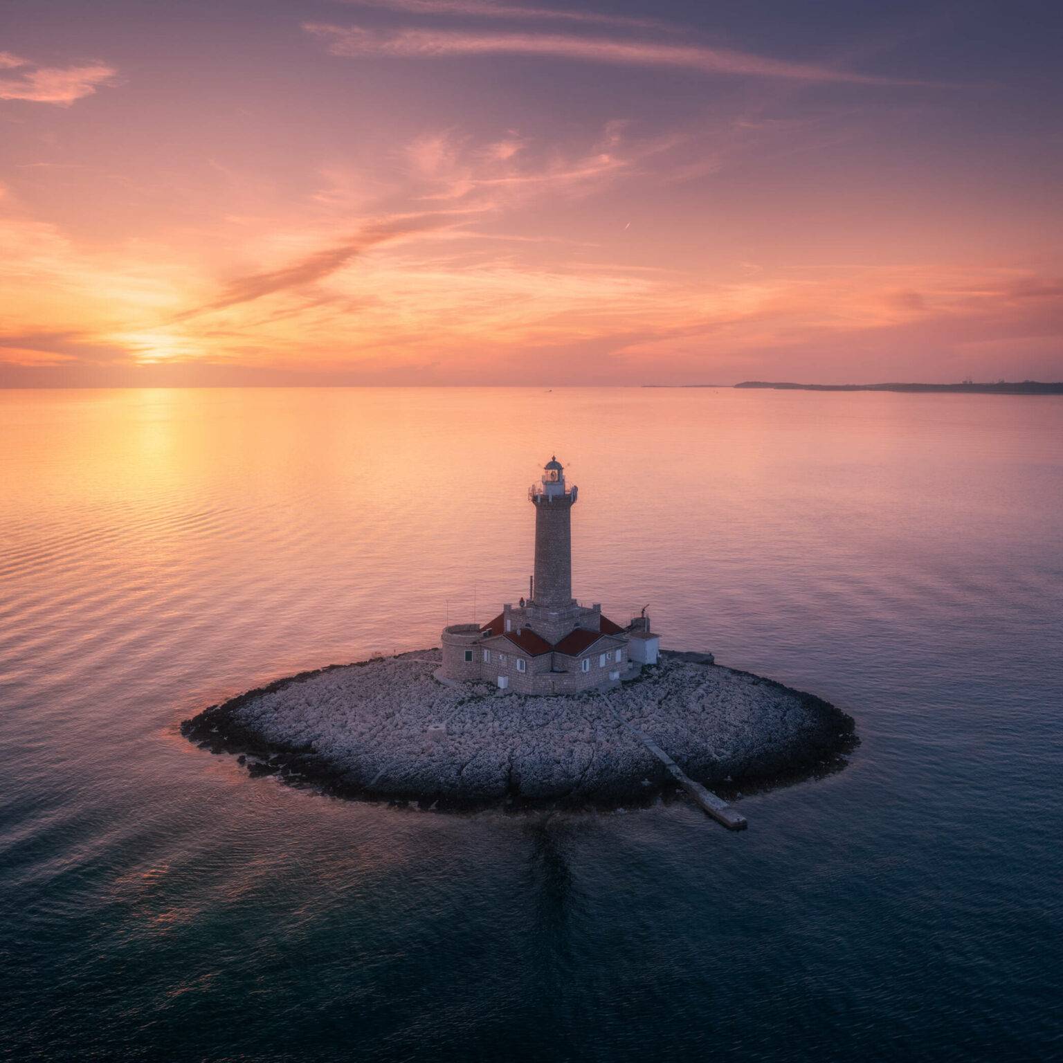 Ein alter Leuchtturm auf einer kleinen Insel in der Adria bei Pula bei Sonnenuntergang.