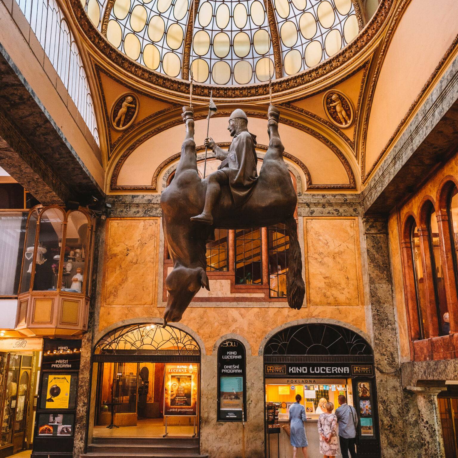 Ein kopfüberhängendes Pferd mit einem Reiter auf dem Bauch bildet das Denkmal der Wenzel-Statue in der Lucerna Passage in Prag.